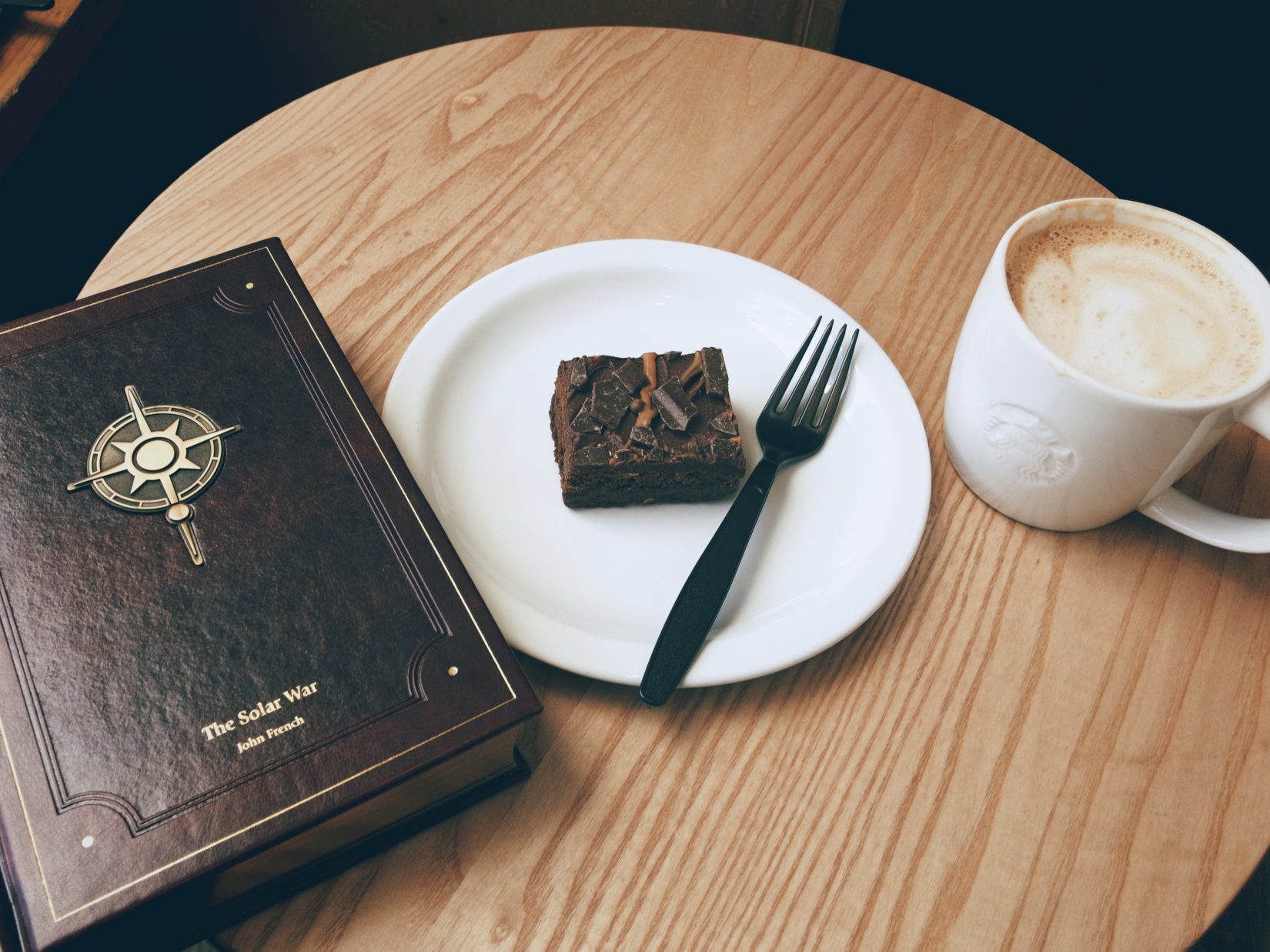 Book, caramel brownie, and latté, on a coffee table